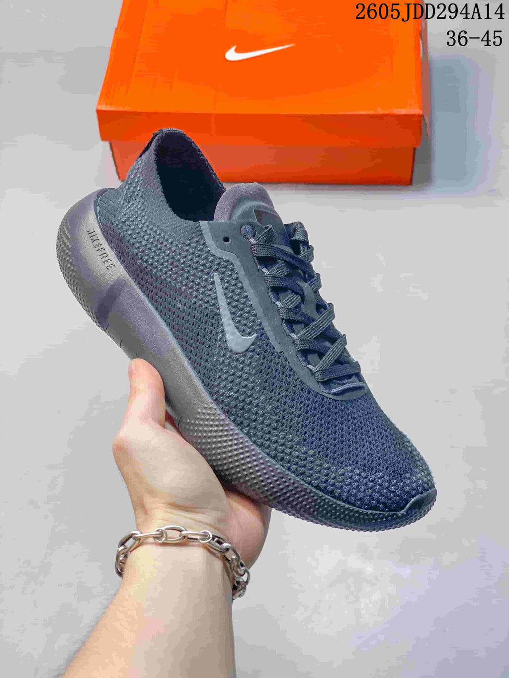 Angled side view of the dark gray Nike Free sneaker showing the knit-style upper, Swoosh, heel padding, and outsole grooves.