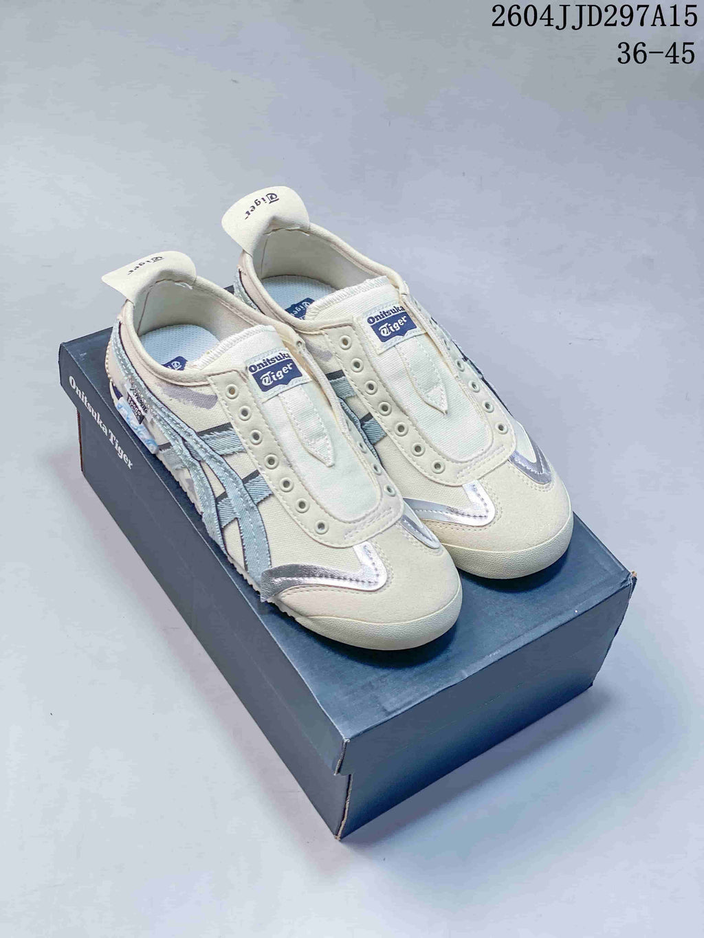Pair of cream and pale blue Onitsuka Tiger sneakers displayed on a branded shoe box; style code 2604JJD297A15 and size range 36-45 are visible.
