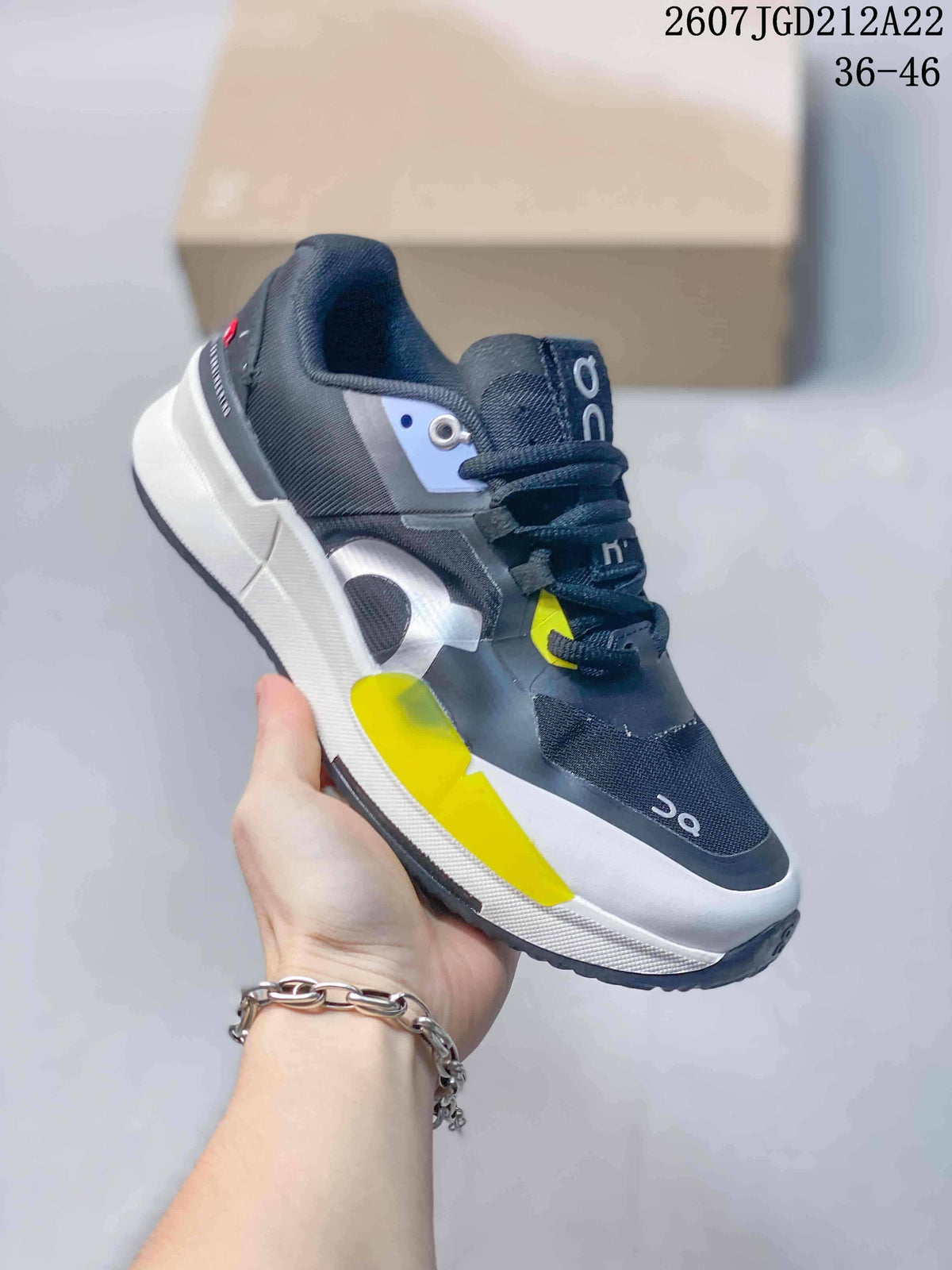 Angled side view of the black, white, and yellow On sneaker with layered upper panels and thick white midsole.