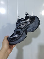 Rear three-quarter view of the black and grey sneaker, showing the textured heel, mesh upper, pull tabs, and outsole.