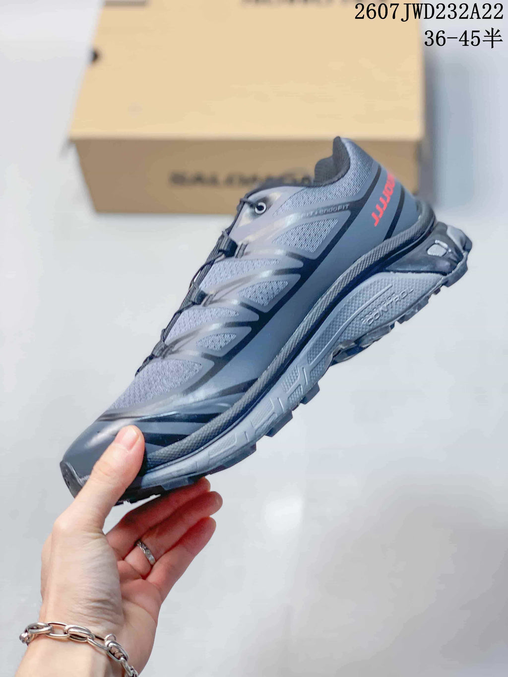 Side profile of the gray and black sneaker showing layered panels, textile-looking sections, and a lugged sole.