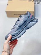 Side profile of the gray and black sneaker showing layered panels, textile-looking sections, and a lugged sole.