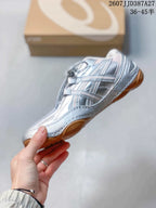 Side profile of the silver low-top sneaker showing layered overlays, laces, and the low-profile outsole.