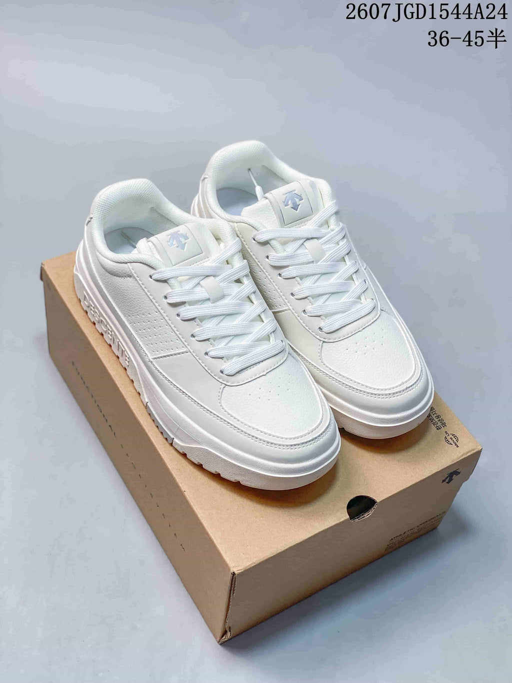 Pair of white DESCENTE Dualis low-top sneakers displayed on a shoebox.