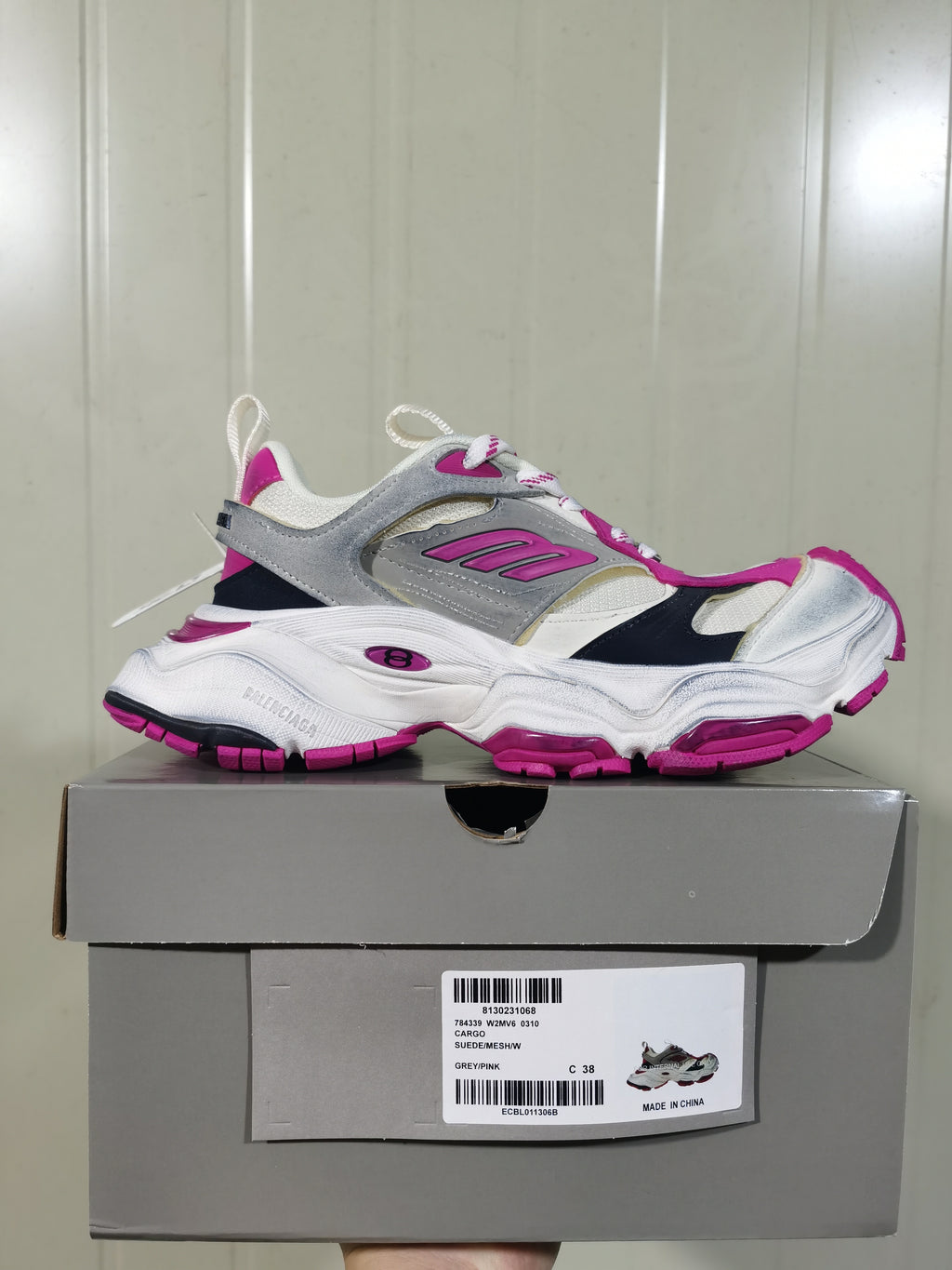 Side view of the Balenciaga sneaker resting on its box; the box label shows Grey/Pink, style code 0310 and size C 38.