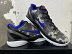 Pair of gray camouflage Nike basketball shoes arranged to show the blue Swoosh, black laces, and white soles.