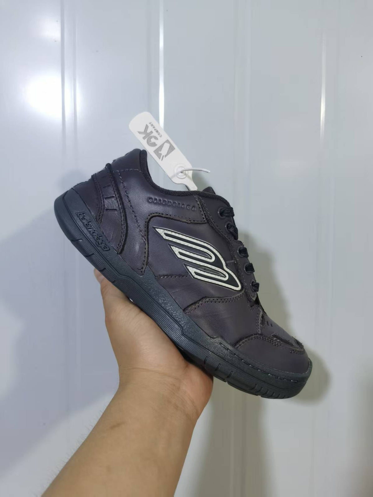 Three-quarter view of the grey sneaker showing the heel panel, side logo, laces and grooved outsole.