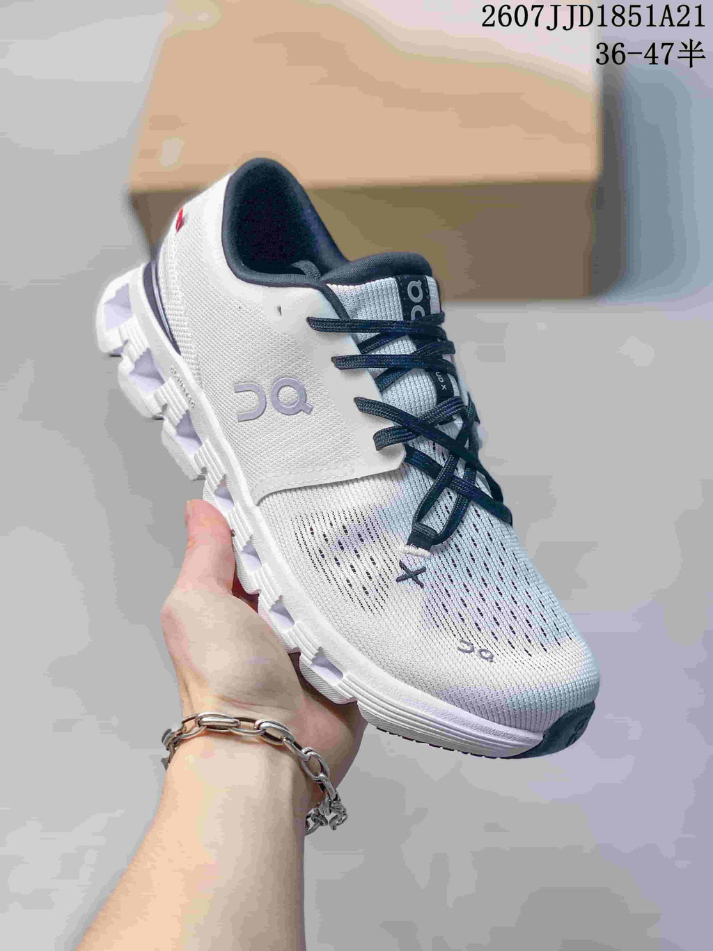 Front three-quarter view of the white and navy sneaker showing the perforated upper, side branding, laces, and cushioned sole.