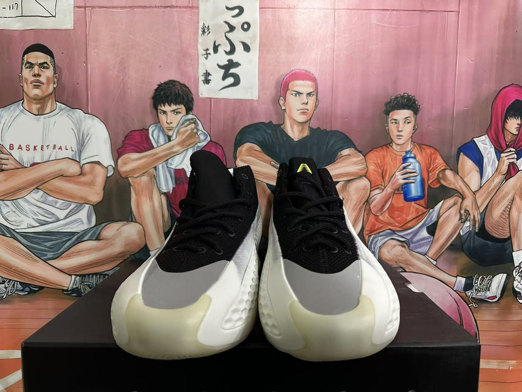 Front view of black basketball shoes with gray and white toe panels and lime tongue detail
