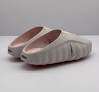 Rear three-quarter view showing the open-back design, side Nike branding, pink footbeds, and orange outsole details.