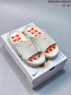 Pair of light-colored Nike Mind 001 slide sandals with orange footbed details on a shoebox