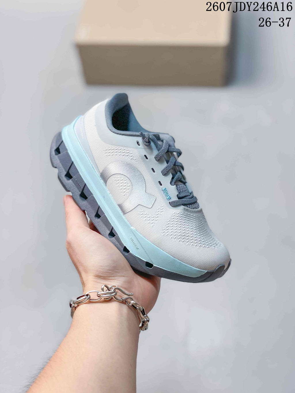 White and pale blue On Cloudstratus 3 kids running shoe with gray laces and a textured upper.