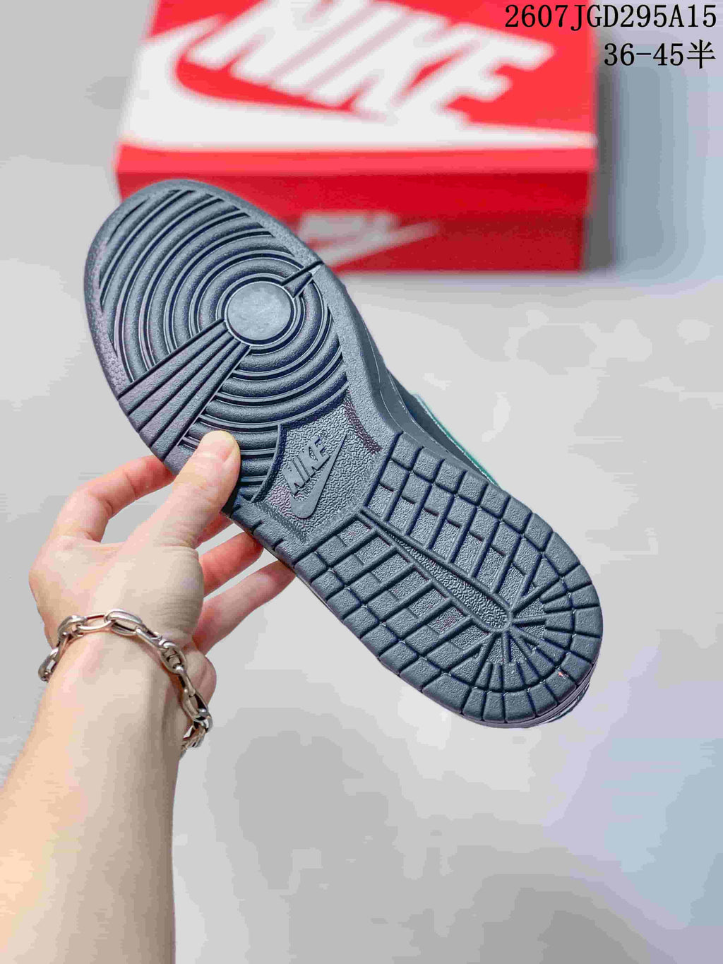 Close view of the black rubber outsole showing circular forefoot and segmented tread patterns, with a red Nike shoebox in the background.