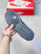 Close view of the black rubber outsole showing circular forefoot and segmented tread patterns, with a red Nike shoebox in the background.