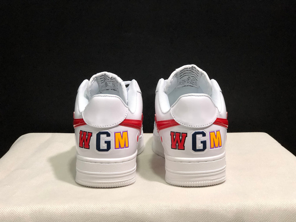 Rear view of the white sneakers showing red heel accents and multicolored WGM lettering.