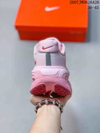 Rear view of the pink sneaker showing the padded heel, heel branding, segmented outsole, and visible size-range text in the background.