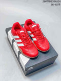 Pair of red adidas Adipista sneakers with white stripes displayed on a shoebox.