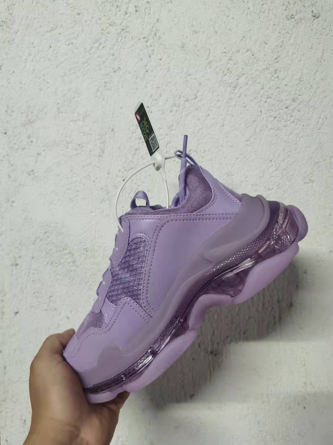 Side and heel view of the purple Balenciaga Triple S sneaker, showing layered panels and the segmented sole.