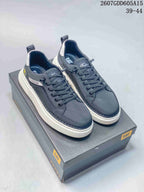 Pair of charcoal CAT casual sneakers displayed on a CAT shoe box with contrasting white outsoles.