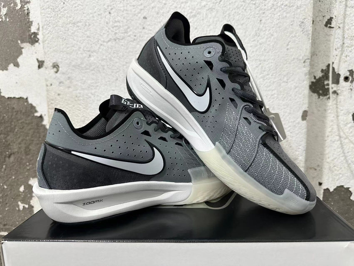 Pair of black and grey low-top shoes displayed at an angle, showing the side logos, patterned panels, and white midsoles.