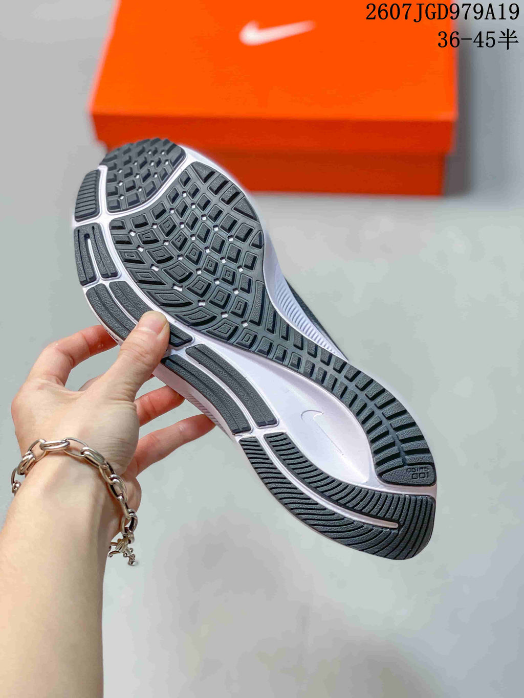 Close view of the sneaker outsole showing a segmented patterned tread with dark rubber sections and a white midsole.