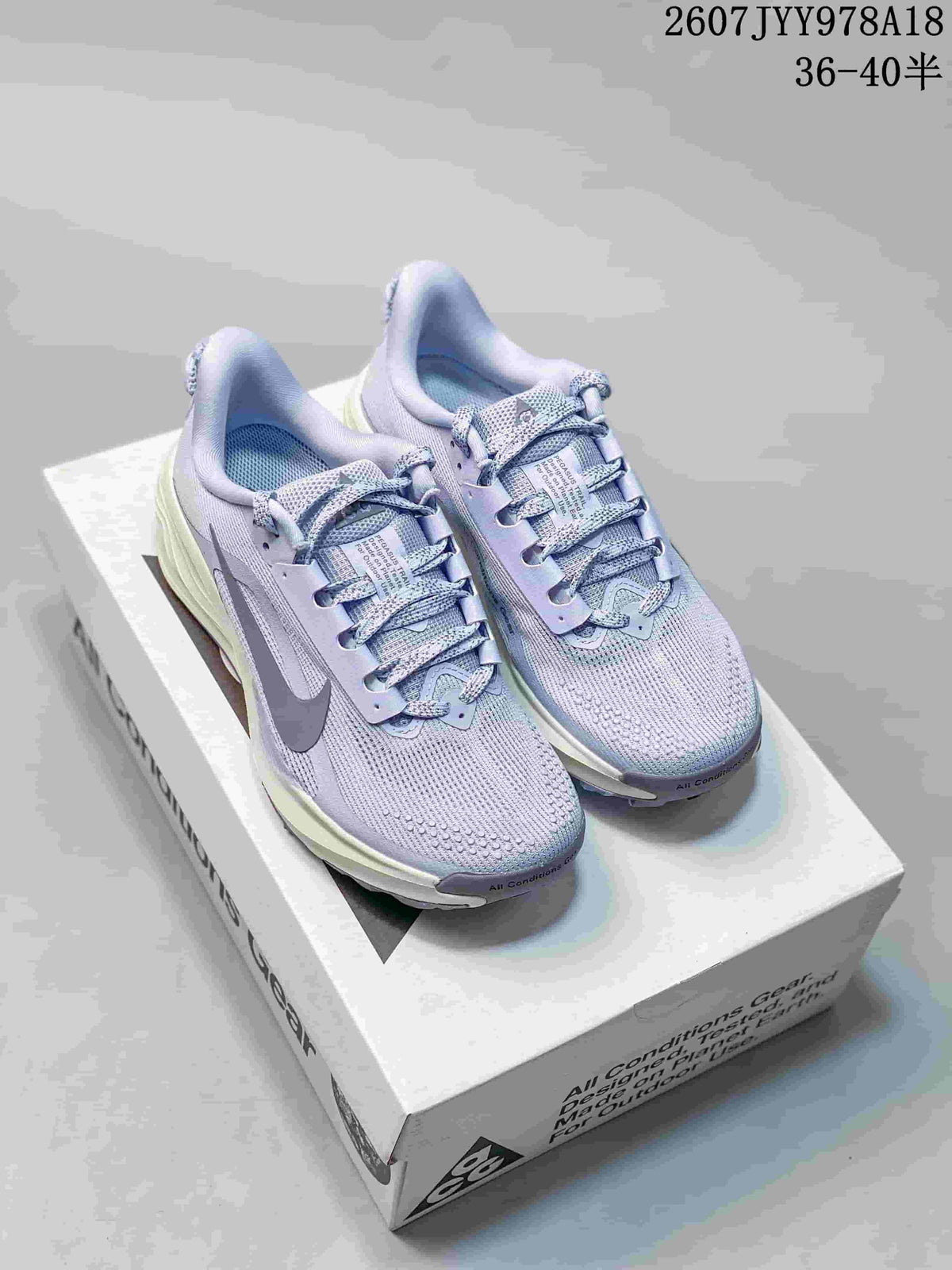 Pair of light lavender Nike ACG Pegasus Trail sneakers displayed on an ACG shoebox, with the size range and style code overlaid.
