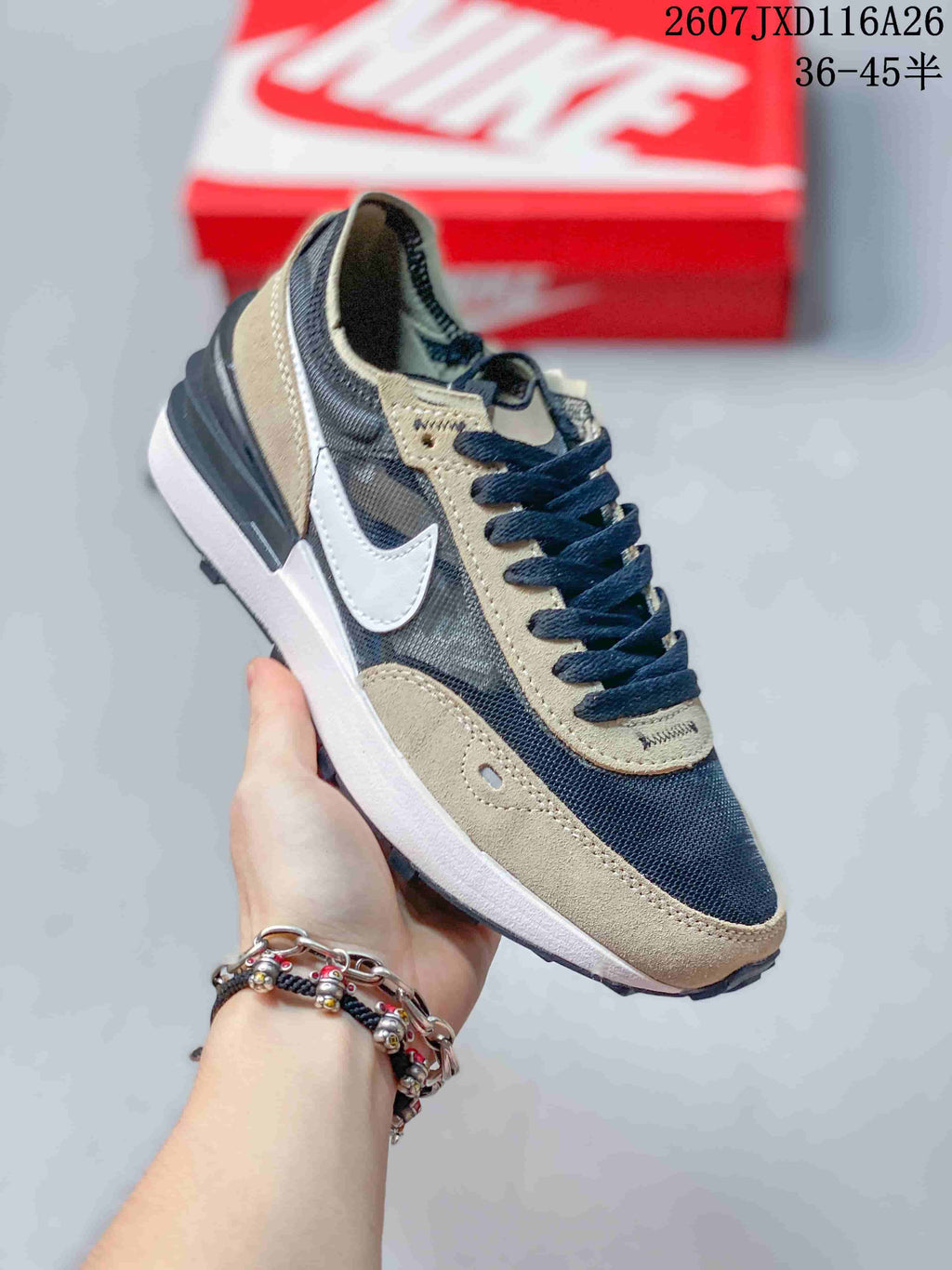 Angled side view of the Nike Waffle One GS sneaker showing the white Swoosh, brown overlays, dark upper panels, and textured outsole.