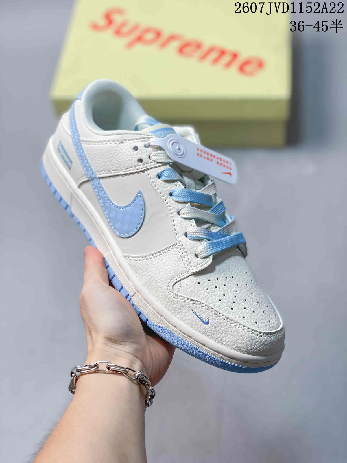 Angled side view showing the white and light blue low-top sneaker with layered panels and Swoosh branding.