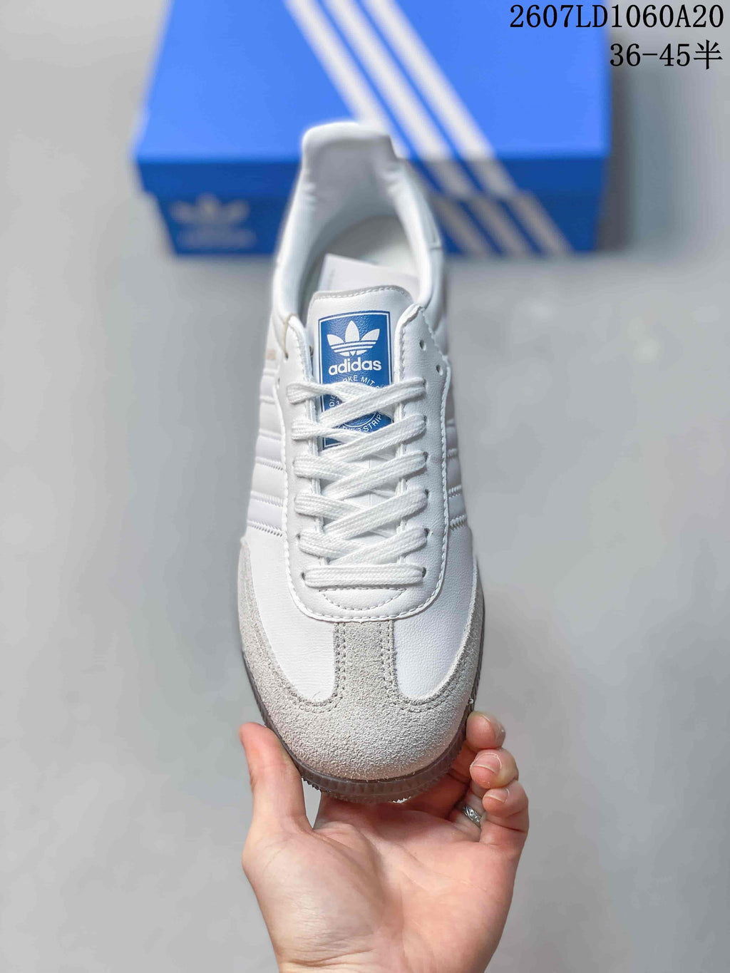 Top view of the sneaker showing white laces, a blue Adidas tongue label, and gray textured toe panels.