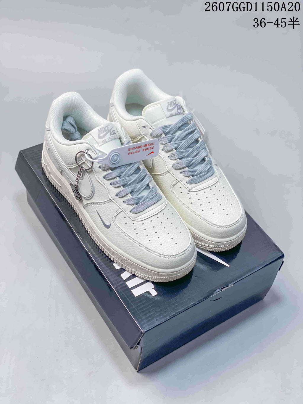 Pair of white Nike low-top sneakers with pale gray laces and light gray Swoosh details displayed on a shoebox.