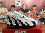 Side view showing layered panels, gold-tone Swoosh, black accents, and visible cushioning.