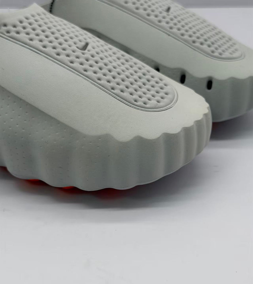 Close-up of the perforated gray footbed and scalloped front edge of the slide sandal.