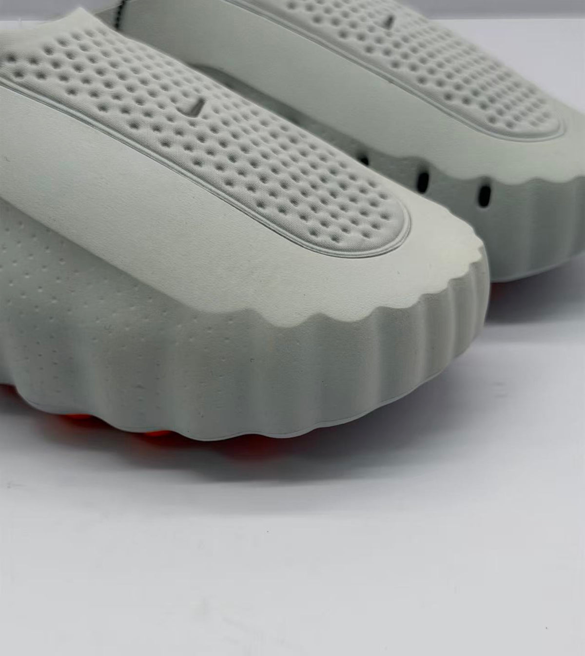 Close-up of the perforated gray footbed and scalloped front edge of the slide sandal.