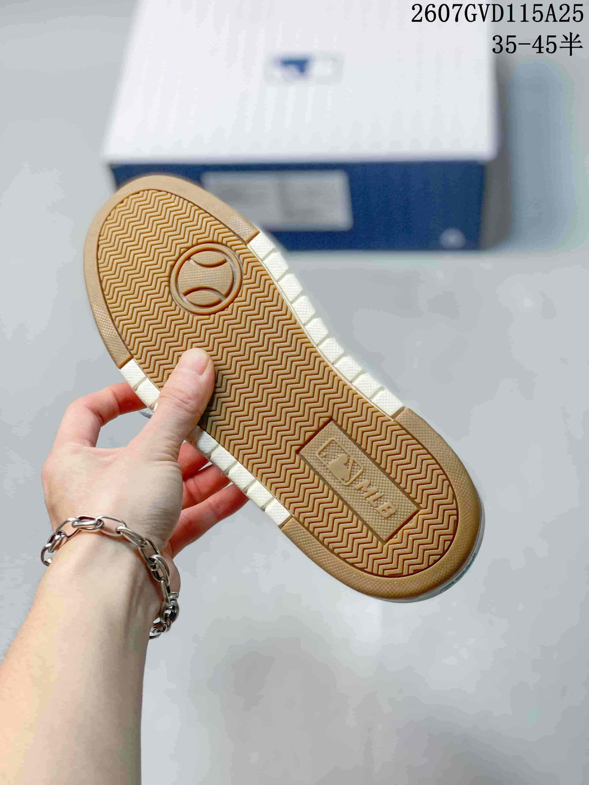 Close-up of the sneaker outsole showing a brown herringbone tread pattern and molded central detail.
