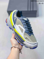 Close-up of a gray, navy, white, and neon yellow OZWEEGO sneaker showing layered mesh and panel construction.