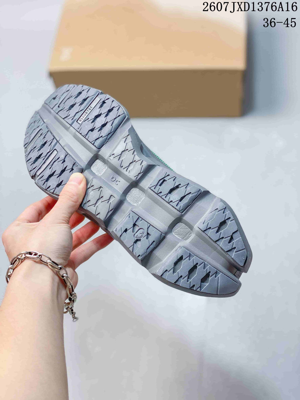 Underside view of the sneaker showing the gray patterned outsole with segmented tread blocks.