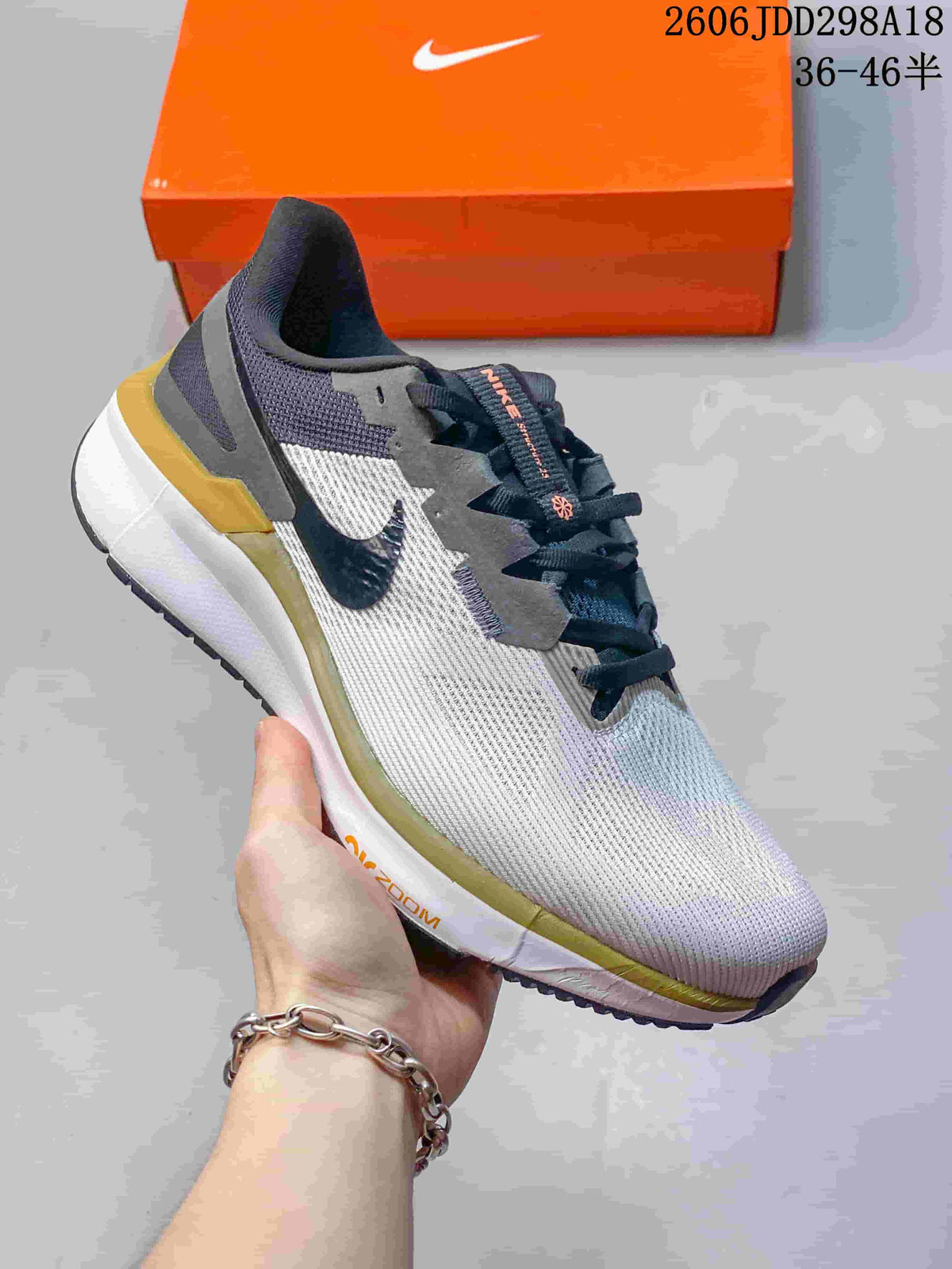 Angled side view of the sneaker showing the white upper, dark overlays, Swoosh branding and gold outsole accents.