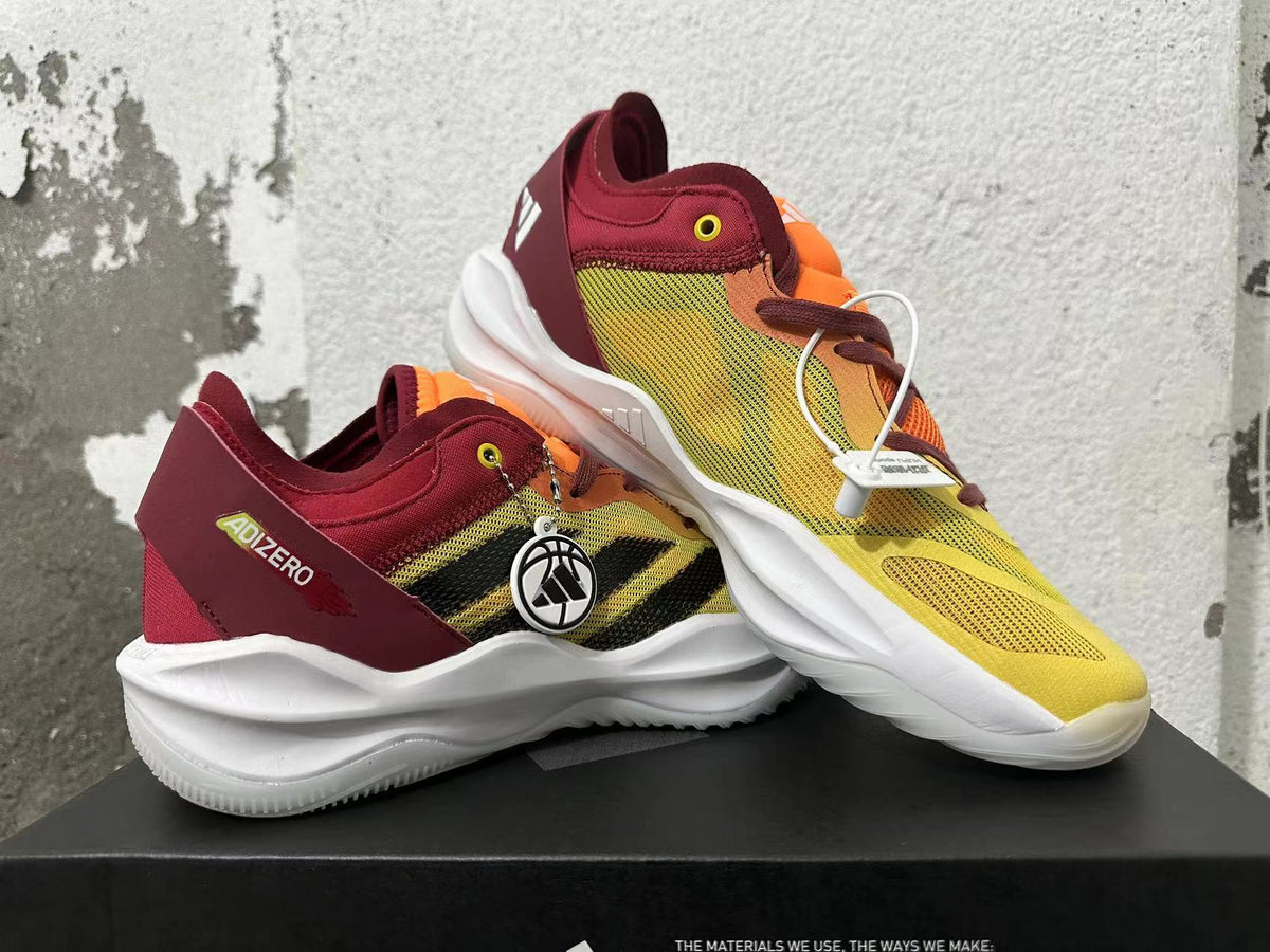 Pair of yellow, orange, and burgundy adidas Adizero sneakers shown at an angle.