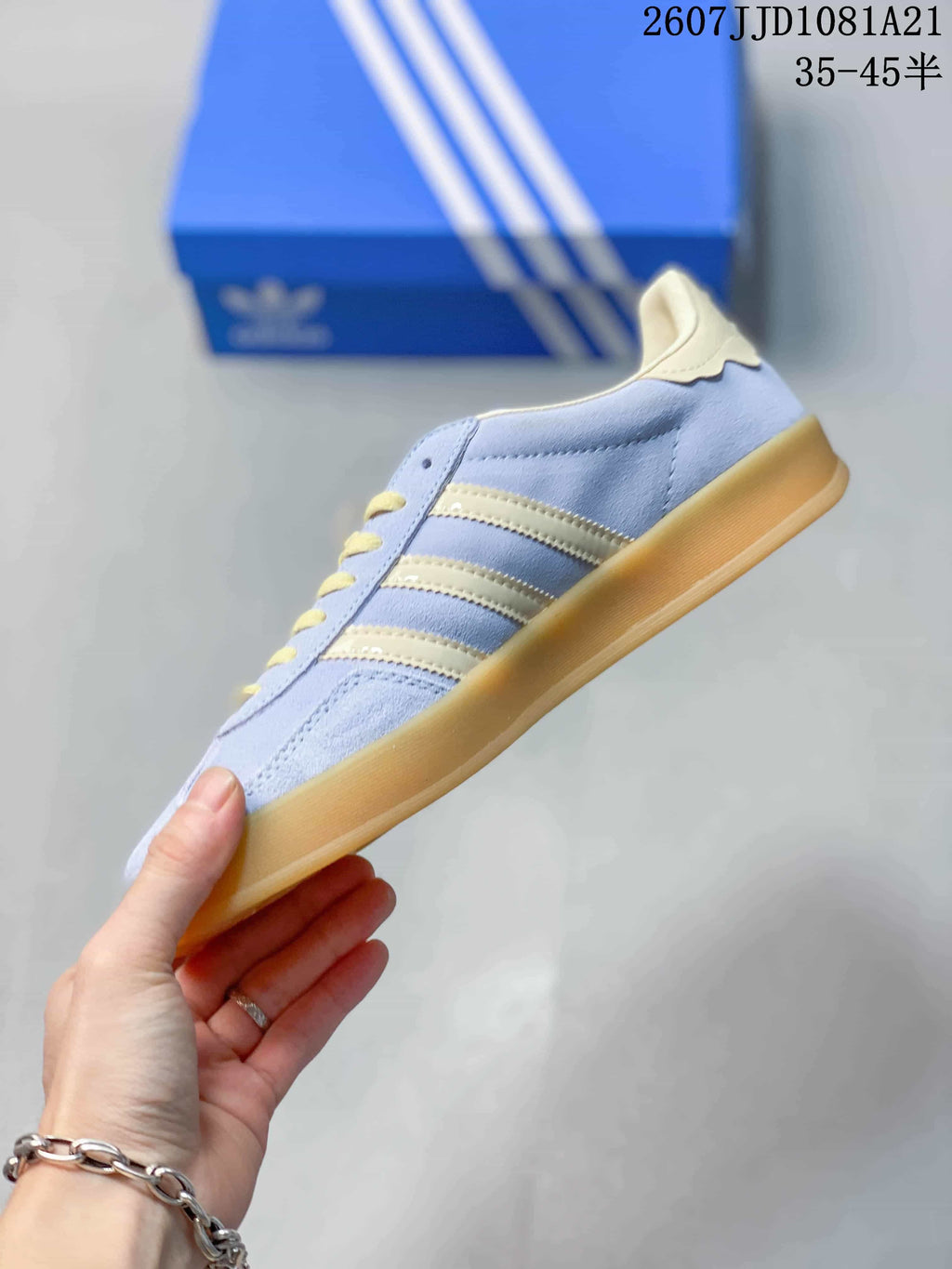 Side profile showing the light blue upper, cream three stripes, yellow laces, and gum-colored sole.