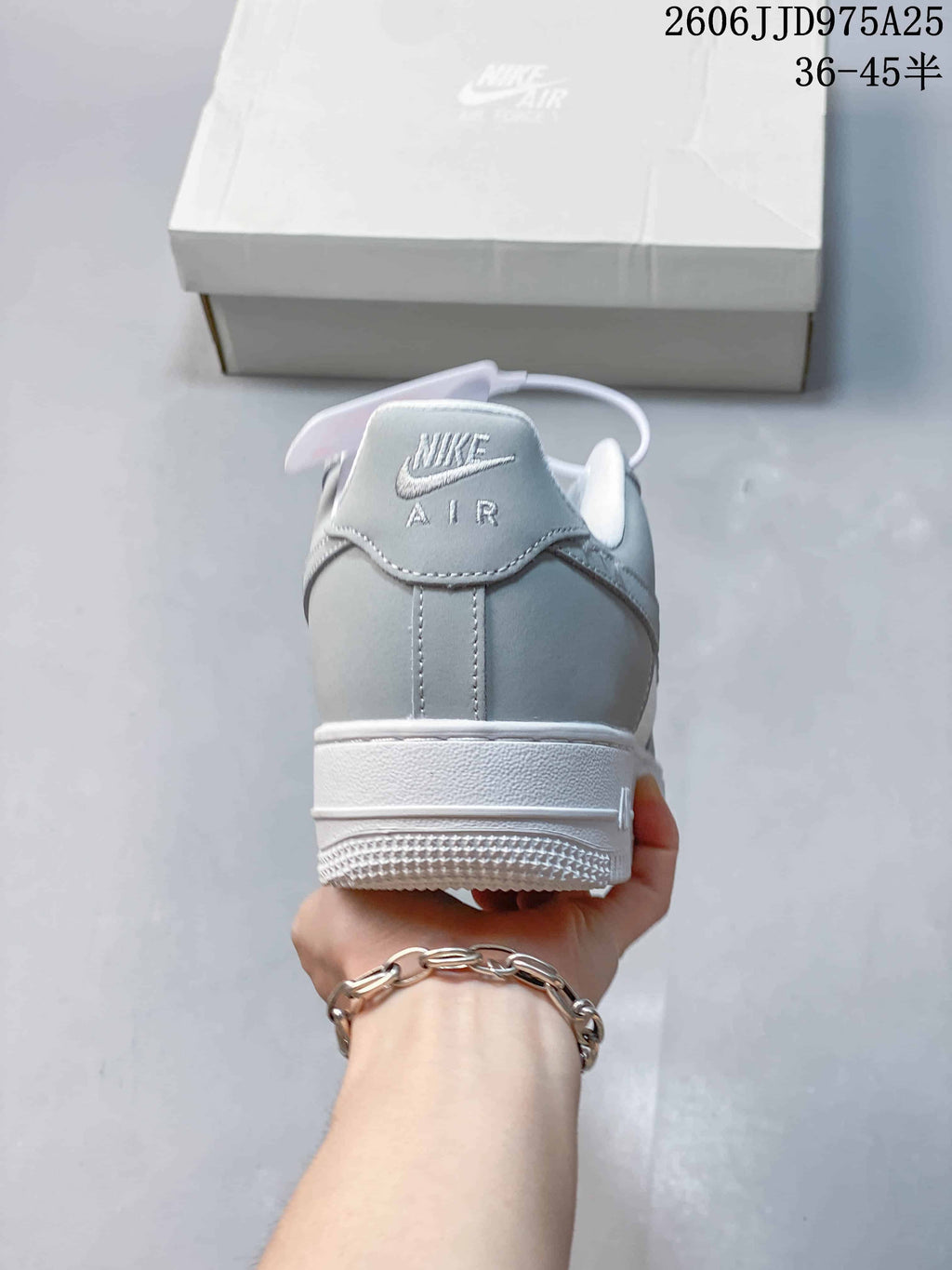 Rear view of the light grey and white sneaker showing the Nike Air heel logo and layered heel construction.