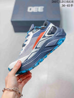 Side view of the trail shoe showing the gray mesh-style upper, white overlays, orange accent, and blue outsole lugs.