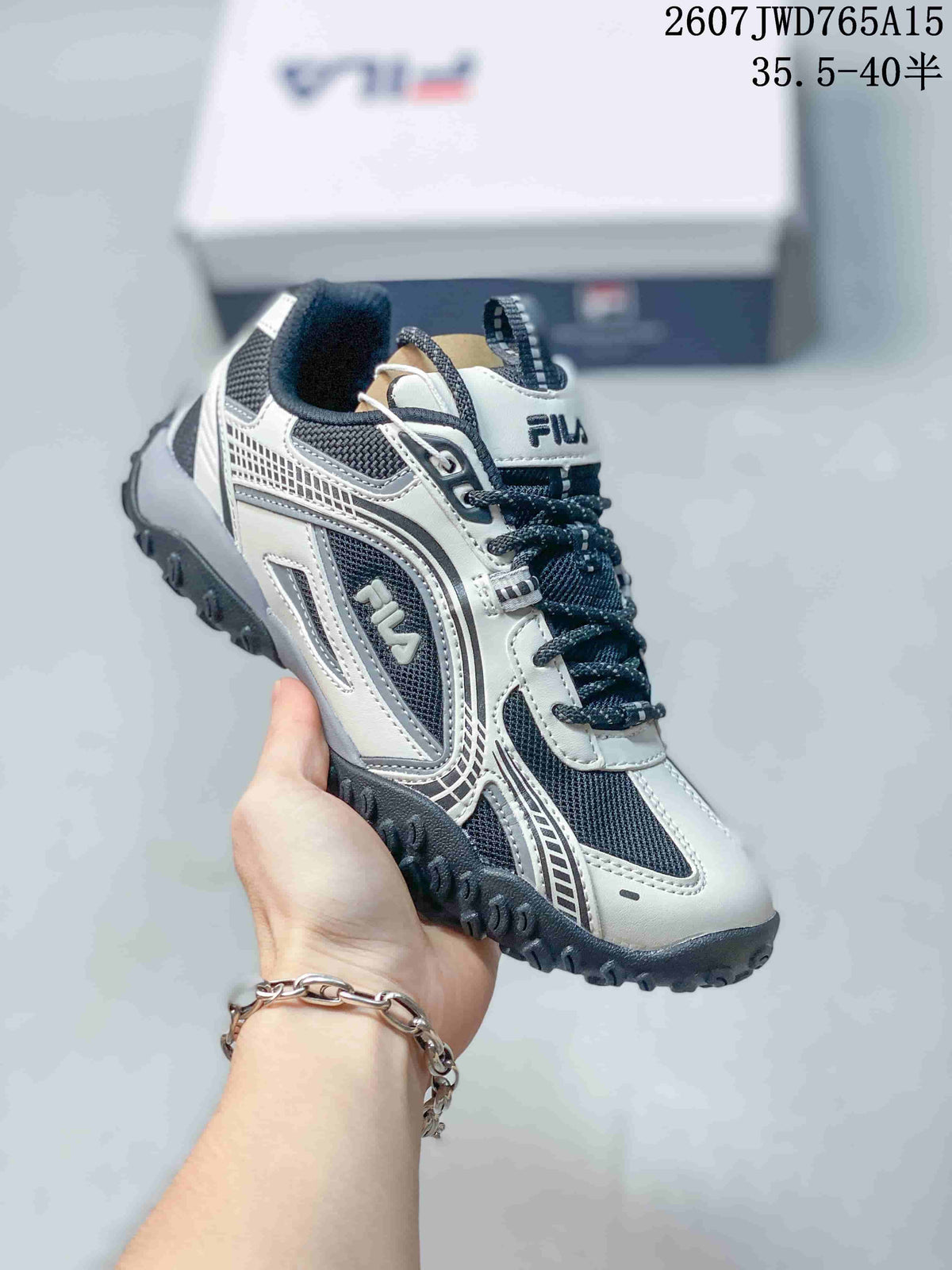 Angled side view of a black-and-white FILA Pebble sneaker showing the FILA side logo, layered detailing, and rugged textured outsole; overlay shows style code 2607JWD765A15 and size range 35.5–40.5.