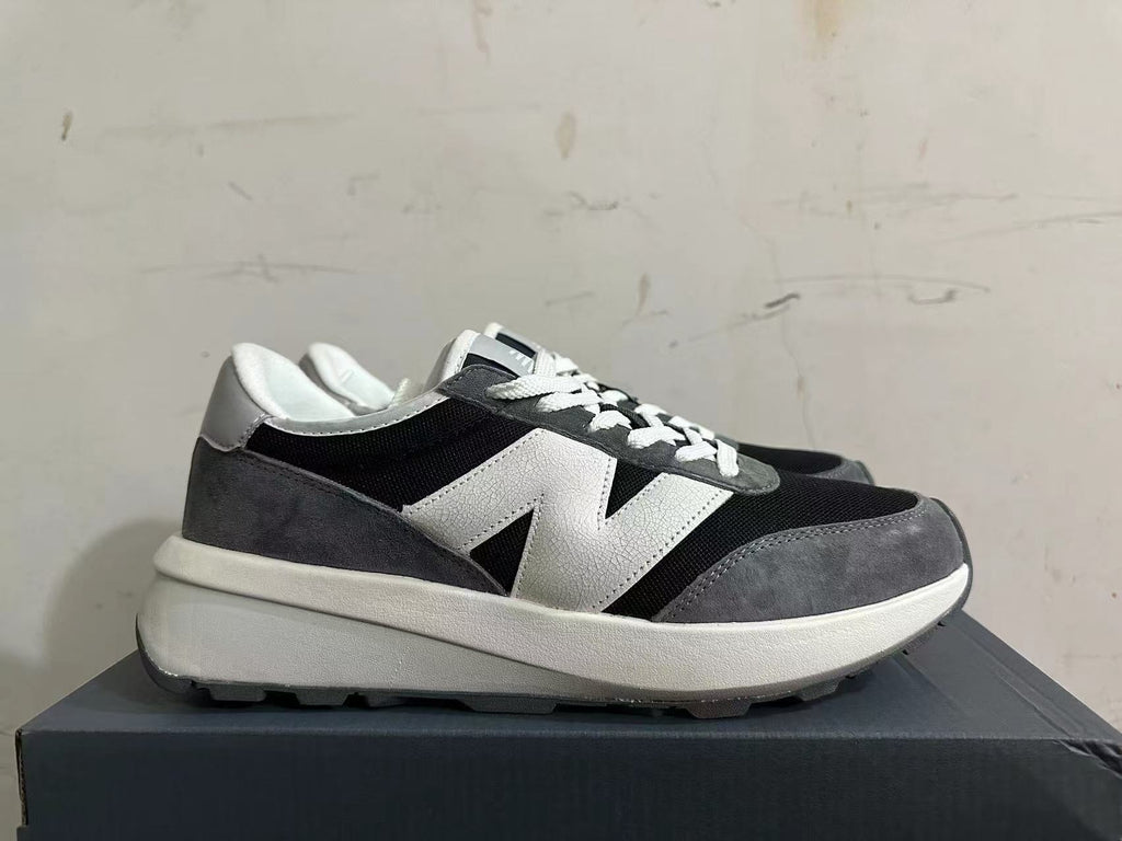 Side profile of New Balance U370 sneakers in black, gray, and white