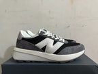 Side profile of New Balance U370 sneakers in black, gray, and white