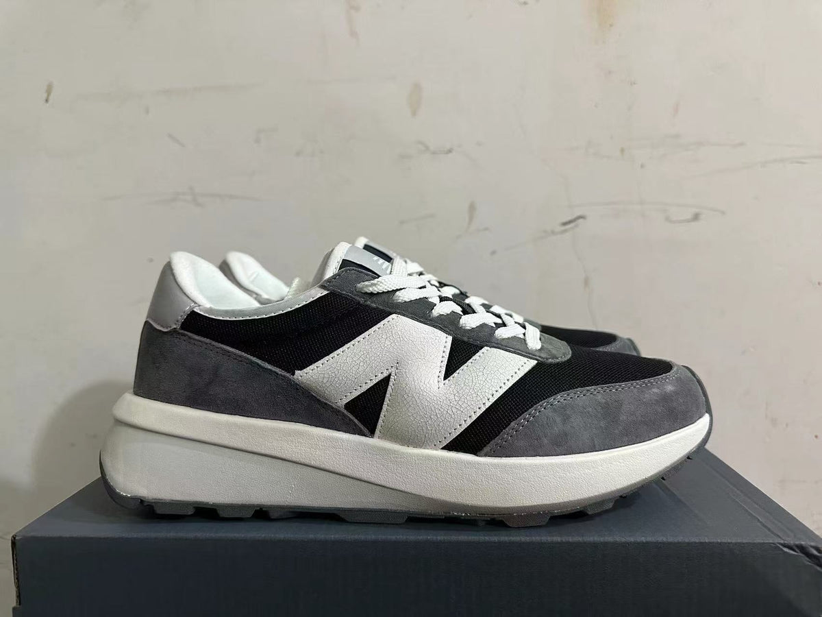 Side profile of New Balance U370 sneakers in black, gray, and white