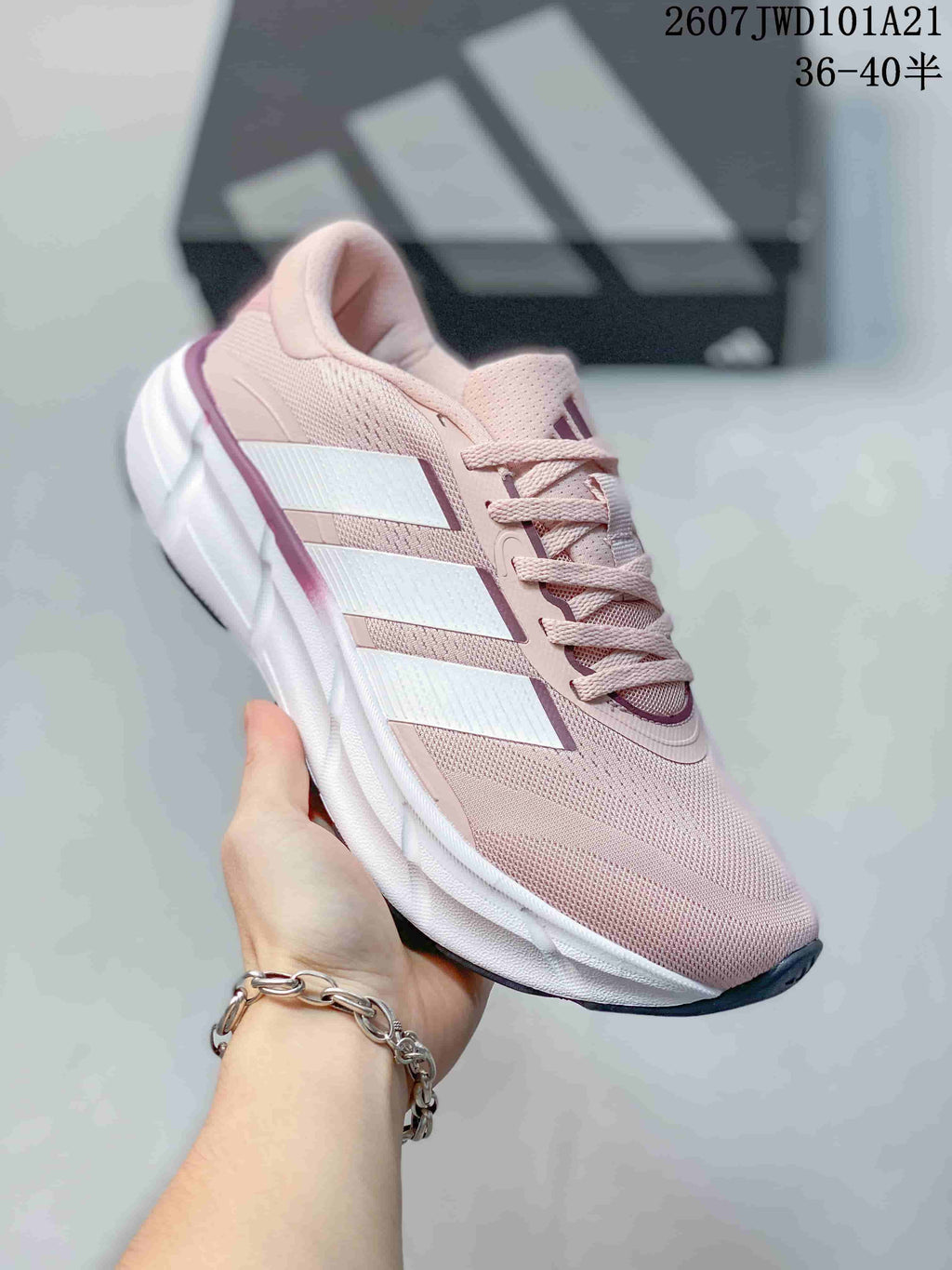 Angled side view of the pink Adidas sneaker showing the mesh-like upper appearance, white side stripes and white midsole.