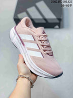 Angled side view of the pink Adidas sneaker showing the mesh-like upper appearance, white side stripes and white midsole.