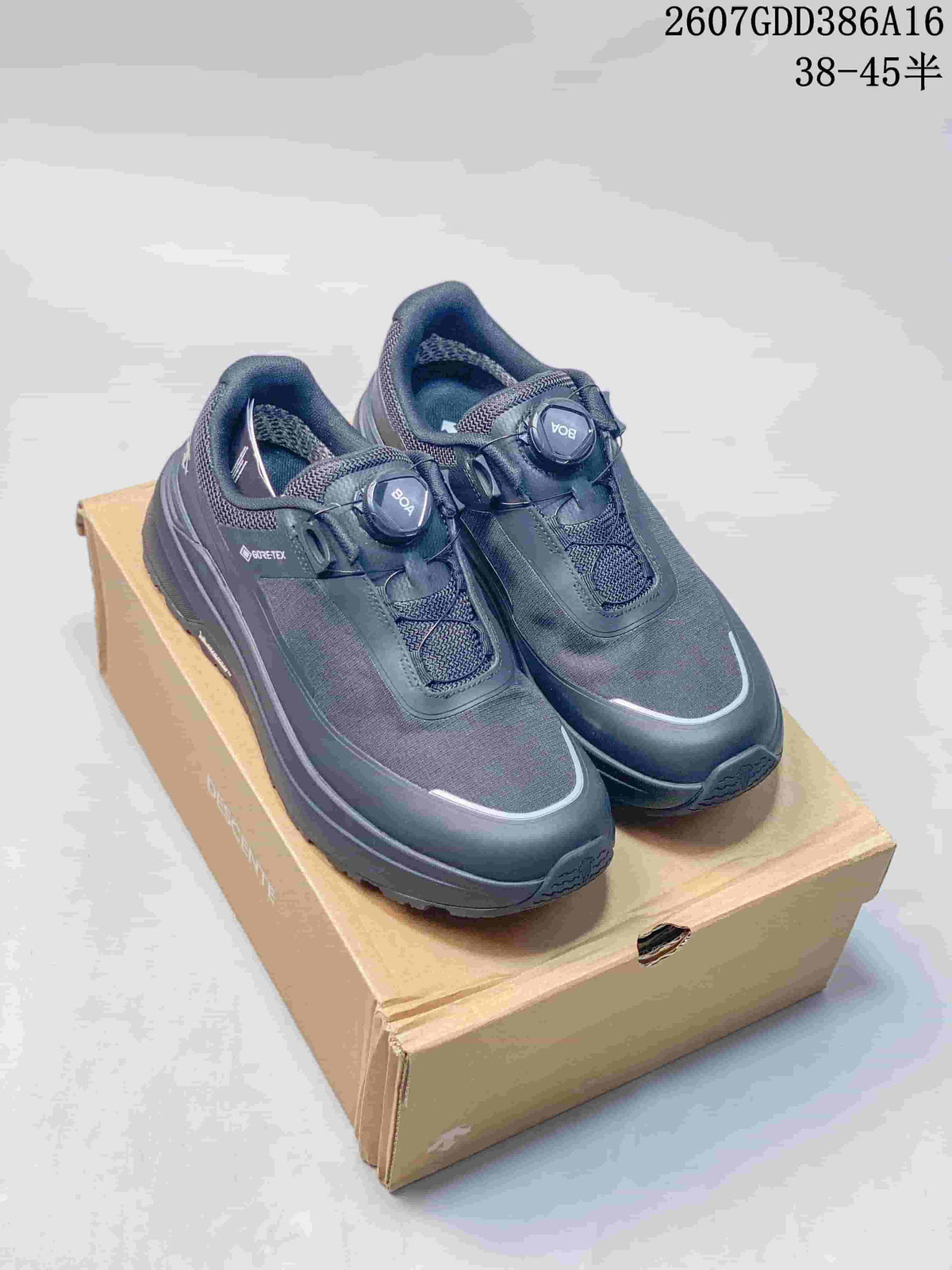 Black Descente low-top sneakers displayed on a shoebox, showing the BOA-style dial closure and reflective-looking toe trim; image text lists style code 2607GDD386A16 and sizes 38–45.5.