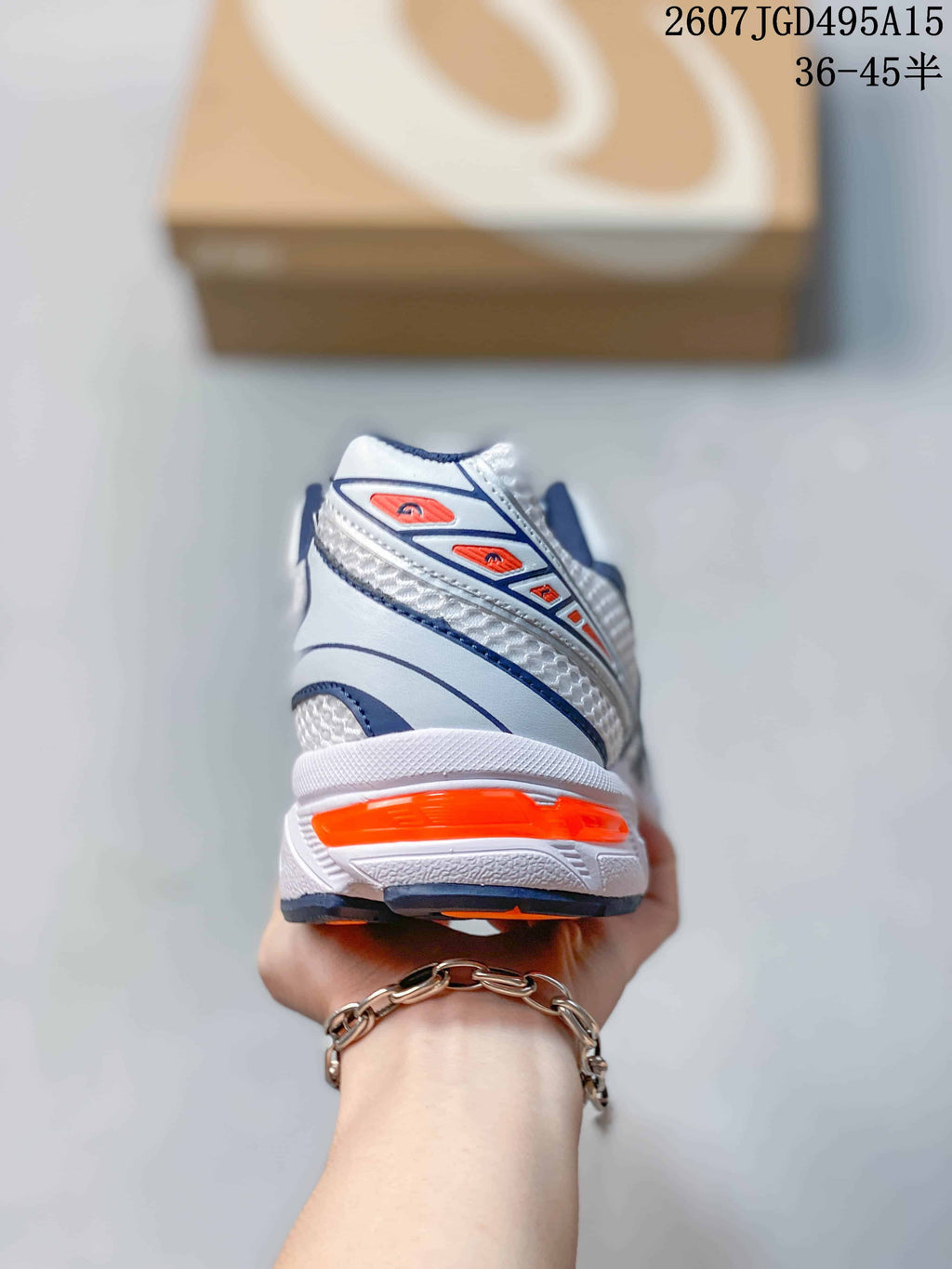 Rear view of the white ASICS sneaker showing the layered heel construction and orange heel accent.