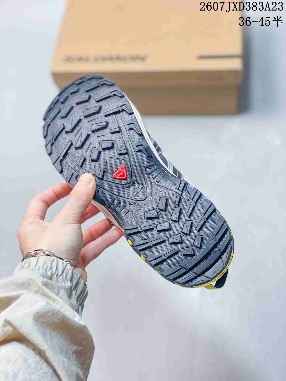 Close view of the Salomon sneaker outsole showing a dark lugged tread pattern and red Salomon branding.